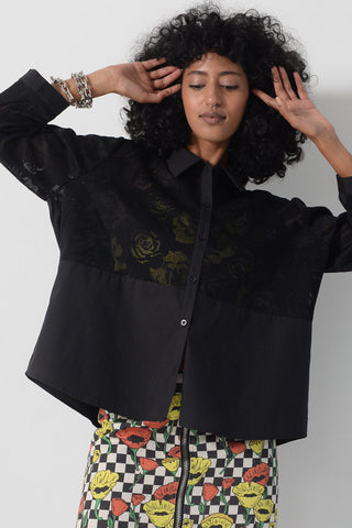 Close-up of model wearing long sleeve black floral button up Stefan Top by Kurt Lyle. 
