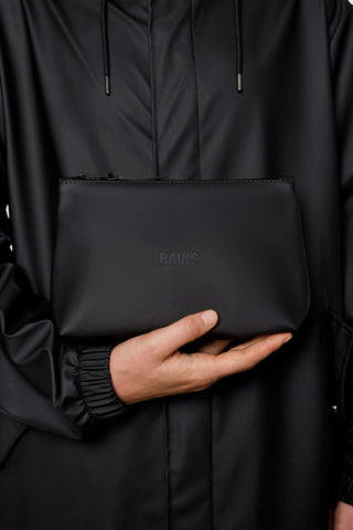 Model holding black unisex waterproof RAINS Cosmetic Bag. 