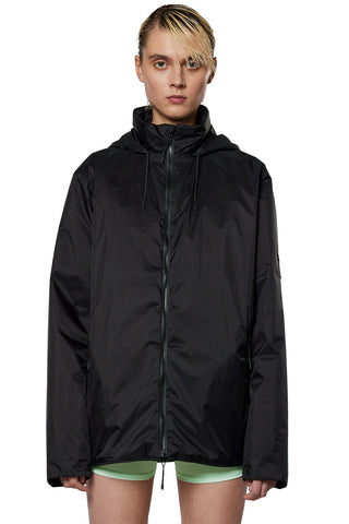 Model wearing black insulated waterproof RAINS Fuse jacket. 
