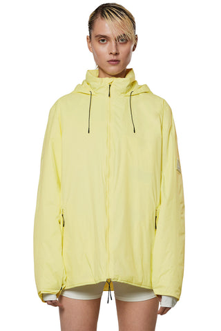Model wearing yellow (straw) insulated waterproof RAINS Fuse jacket. 