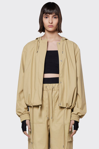 Model wearing lightweight waterproof RAINS String W jacket in beige (sand). 