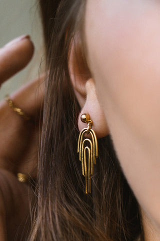 Model wearing gold plated rainbow shaped dangling Rainbow Earring by Tilly Doro.