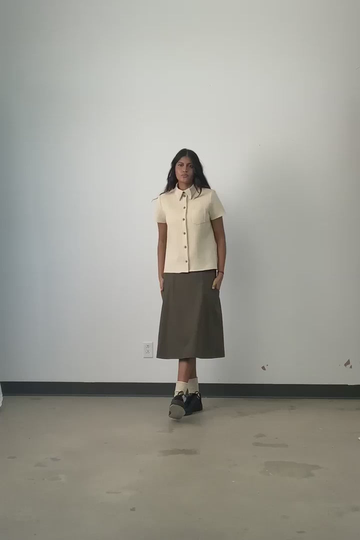 Video of Side view of model wearing Jennifer Glasgow Asherah Button Up in cream organic cotton waffle weave. 