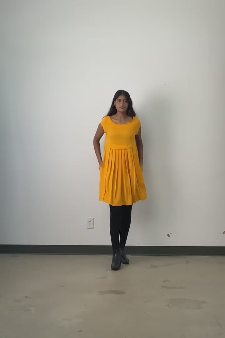 Video of model wearing Jennifer Glasgow Saiwa pleated dress in yellow OEKO-TEK linen blend.
